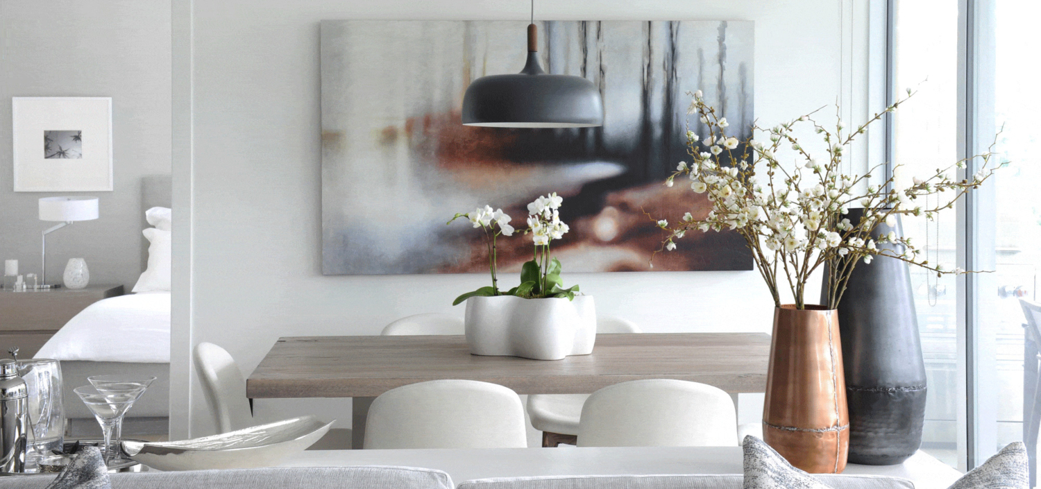 White dinning room with a grey wooden table and decorative flowers in vases
